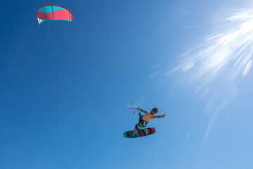 kiter does a difficult trick on a background of transparent water and blue sky