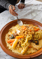 Vertical detail food shot of a traditional moroccan couscous with ingredients; chickpeas, carrot, cauliflower, turnip, zucchini, beef meat, spices, wheat semolina and delicious sauce.