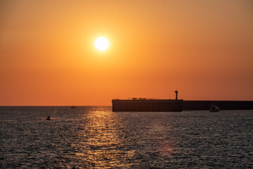 Beautiful yellow and orange sunset over the sea. The sun goes down over the sea. Silhouette of sea port at sunset