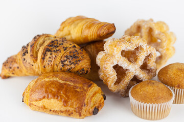 Group of baked sweet pastries on white background. Muffins, pain au chocolat, hazelnut, chocolate and butter croissants and sugar covered fried easter flowers. Spanish and french artisan pastries.