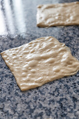 Vertical shot of raw Moroccan flat bread pancakes kitchen preparation on a kneading table with oily squared shapes and negative space. Traditional Moroccan gastronomy cuisine food breakfast.