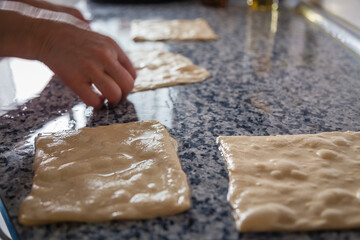 Moroccan flat bread pancakes kitchen preparation on a kneading table with chef hands forming the oily squared shapes. Traditional Moroccan gastronomy cuisine food breakfast.