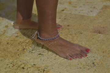 
woman's foot with anklet in the pool water