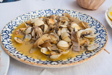 Plate of fresh clams and quality mushrooms with delicious sauce on a bar tableset. Mediterranean seafood gourmet tapas of Andalusia and Granada.