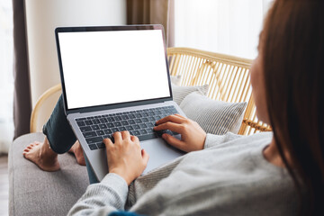 Mockup image of a woman working and typing on laptop computer with blank screen while lying on a sofa at home