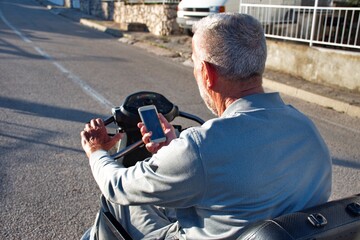 Disabled senior man using mobile phone while driving wheel chair