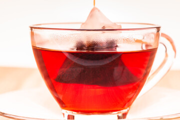 Steeping a pyramid mesh teabag in a glass cup close up