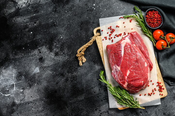 Raw brisket beef cut on a wooden cutting board. Black Angus beef. Black background. Top view. Copy space - obrazy, fototapety, plakaty