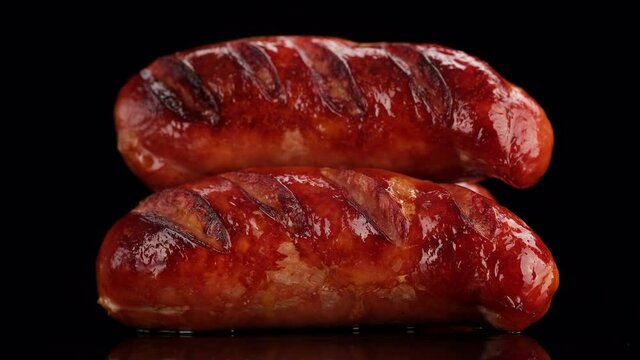 rotating grilled sausage on black background