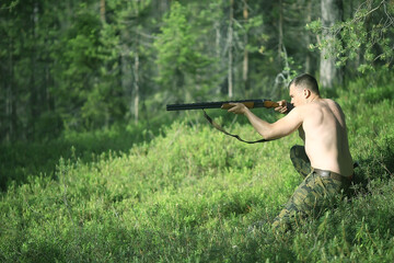 man goes hunting forest summer / landscape in the forest, huntsman with a hunting rifle hunts