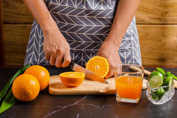Closeup on women cutting orange for make juice on kitchen table.