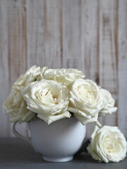 Flower background.A bouquet of white roses in a large white tea Cup on a wooden background.petals