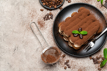 Classic tiramisu dessert on ceramic plate on concrete background