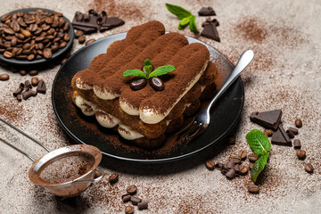Classic tiramisu dessert on ceramic plate on concrete background