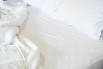 Close-up of clean white soft pillows with duvet and bed sheets on the comfortable bed in the bedroom.