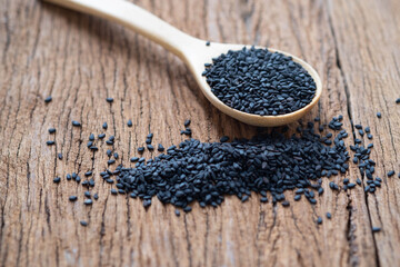 Close-up of Organic natural black sesame seeds in a wooden spoon on wood table background. 