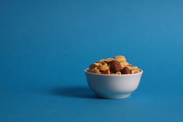 nut mix in white bowl isolated on blue background
