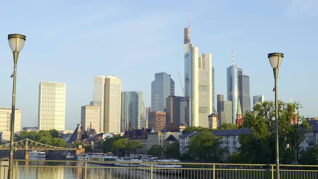 Steady cam moving over a bridge in the city of Frankfurt showing the skyline in the background during sunrise