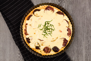 Sheep cheese tart with red onion on wooden background.