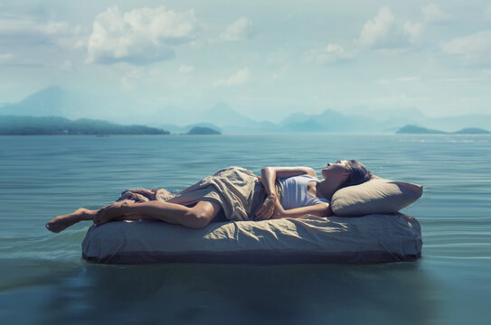 Sleeping woman lies on mattress in a water.