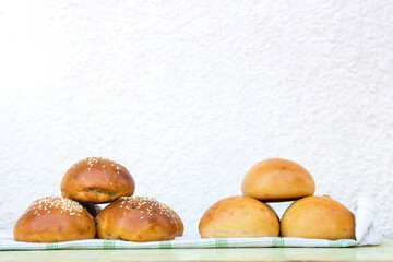 Fresh homemade burger buns on kitchen towel in sunny day.