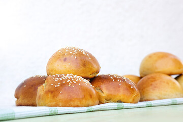 Fresh homemade burger buns on kitchen towel on sunny day.