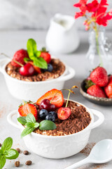 Classic Italian dessert Tiramisu decorated with strawberries, cherries and mint on a white background.