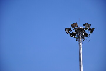 Bunch of spotlight lamps on top of the metal post with bright blue sky, copy space for insert