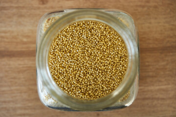 Millet in a glass jar with a spoon, closeup