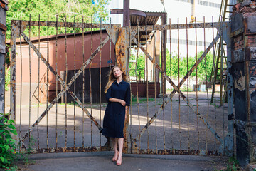 Fashion look's woman near the old rusty gate. Young woman modern portrait.