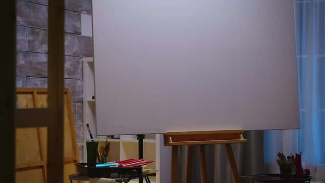 Interior of painting studio with wooden easel and blank canvas. Modern artwork paint on canvas, creative, contemporary and successful fine art artist drawing masterpiece