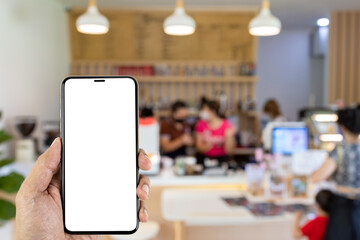 Mockup image of hand holding smartphone with blank white screen on blurred coffee shop with people background.
