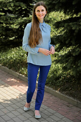 Portrait of a caucasian brunette girl in a park with smile in sunny weather. Universal concept on a background of trees.