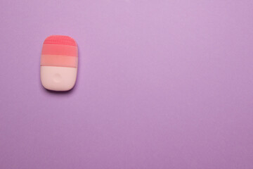 pink electric face massager on pink colored paper background, top view with copy space