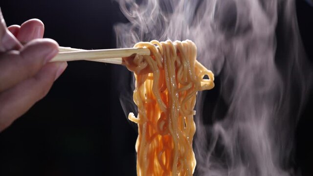 Chopsticks to tasty noodles on dark background