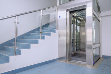 Metal elevator and pedestrian staircase. The concept of choosing a method of moving to the upper floors.The concept of choosing a method of moving to the upper floors.