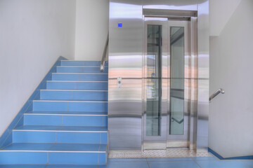Metal elevator and pedestrian staircase. The concept of choosing a method of moving to the upper floors.