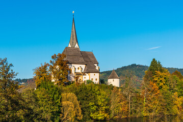 Fototapeta na wymiar Magical Gothic architecture in Austria. Panorama on Lake Worthersee. Maria Worth church and sanctuary.