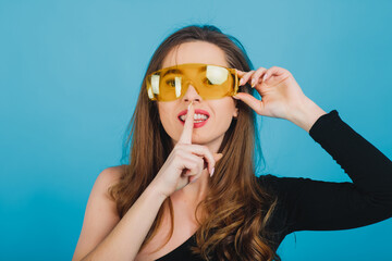 beautiful sporty girl dressed in black bodysuit with yellow glasses on blue background