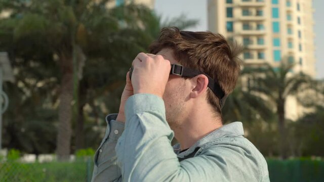 man puts on glass of virtual reality. palms and street. fvp dron