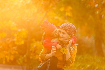 Mother giving daughter piggyback ride in autumn woodland