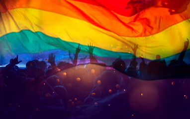 Colorful LGBT flag blows in the breez over crowd.