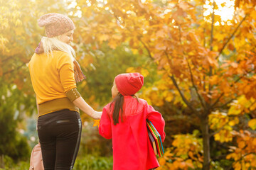 Mom leads her daughter to school. Return to school. Woman and girl with backpack behind the back....
