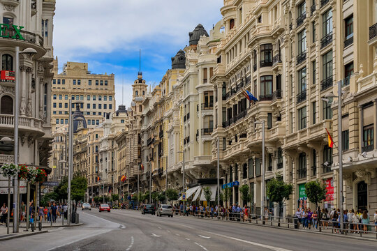 Fototapeta Beautiful buildings on the famous Gran Via shopping street and people walking in the center of the city in Madrid, Spain