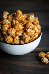Salted caramel popcorn in a white plate on a dark wooden background