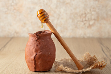 Clay pot with honey stands on a wooden table.