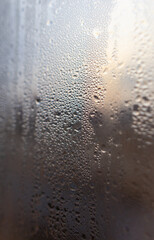 Drops of water on a glass window at dawn as an abstract background.