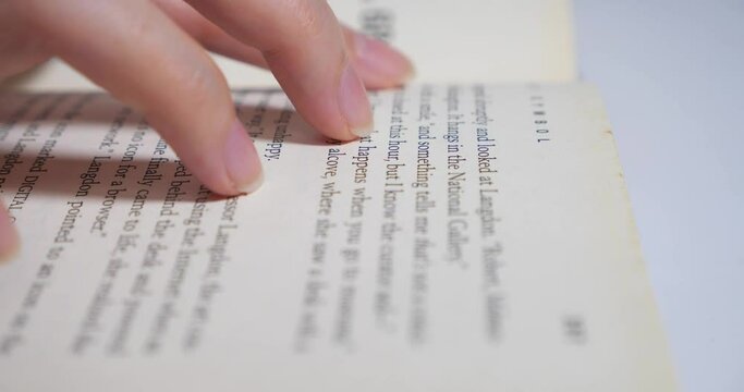Close up shot of hand woman is reading a book on white background. Woman is looking for information in book. Close-up macro shot picture of hand and book isolated white background.