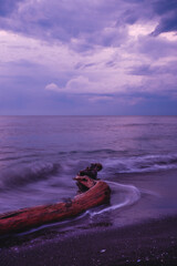 Pink sea sunset and log in the sea. Long-exposure photos.