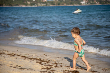 little cute toddler kid runs along the sea beach on a sunny warm day